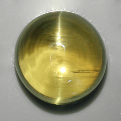 อะพาไทท์ตาแมว (Cat's eye Apatite) 13.87 กะรัต เนื้อใส สีเขียวอมเหลือง รูปร่างกลม เม็ดใหญ่