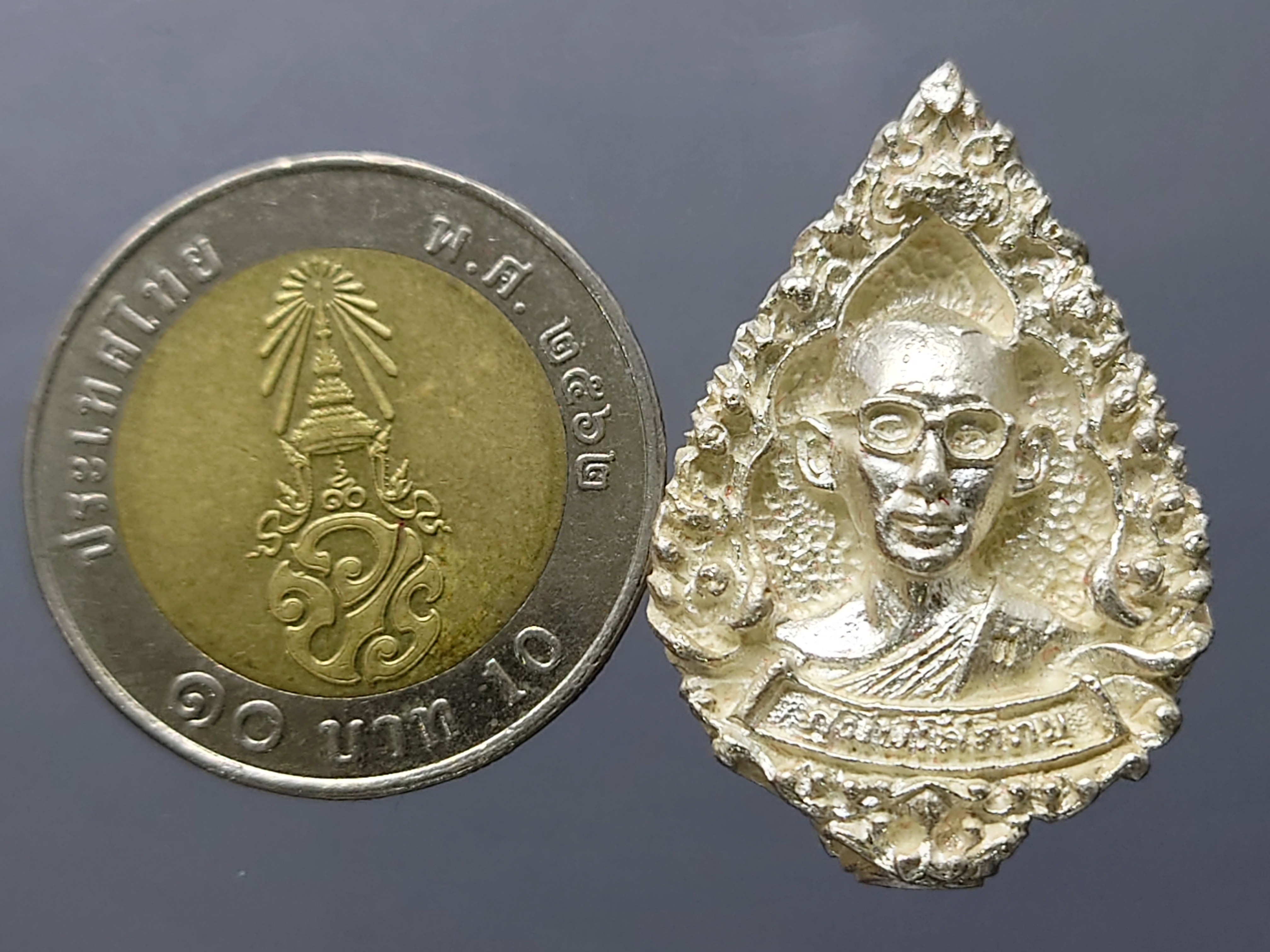 เหรียญในหลวงทรงผนวช เหรียญหล่อฉีด เนื้อเงิน พิมพ์หยดน้ำ สร้างโดยกองพลที่ 1 รักษาพระองค์ หลวงปู่โต๊ะ หลวงปู่ทิม ร่วมปลุกเสก ปี 2517 พร้อมบัตรรับรองพระแท้