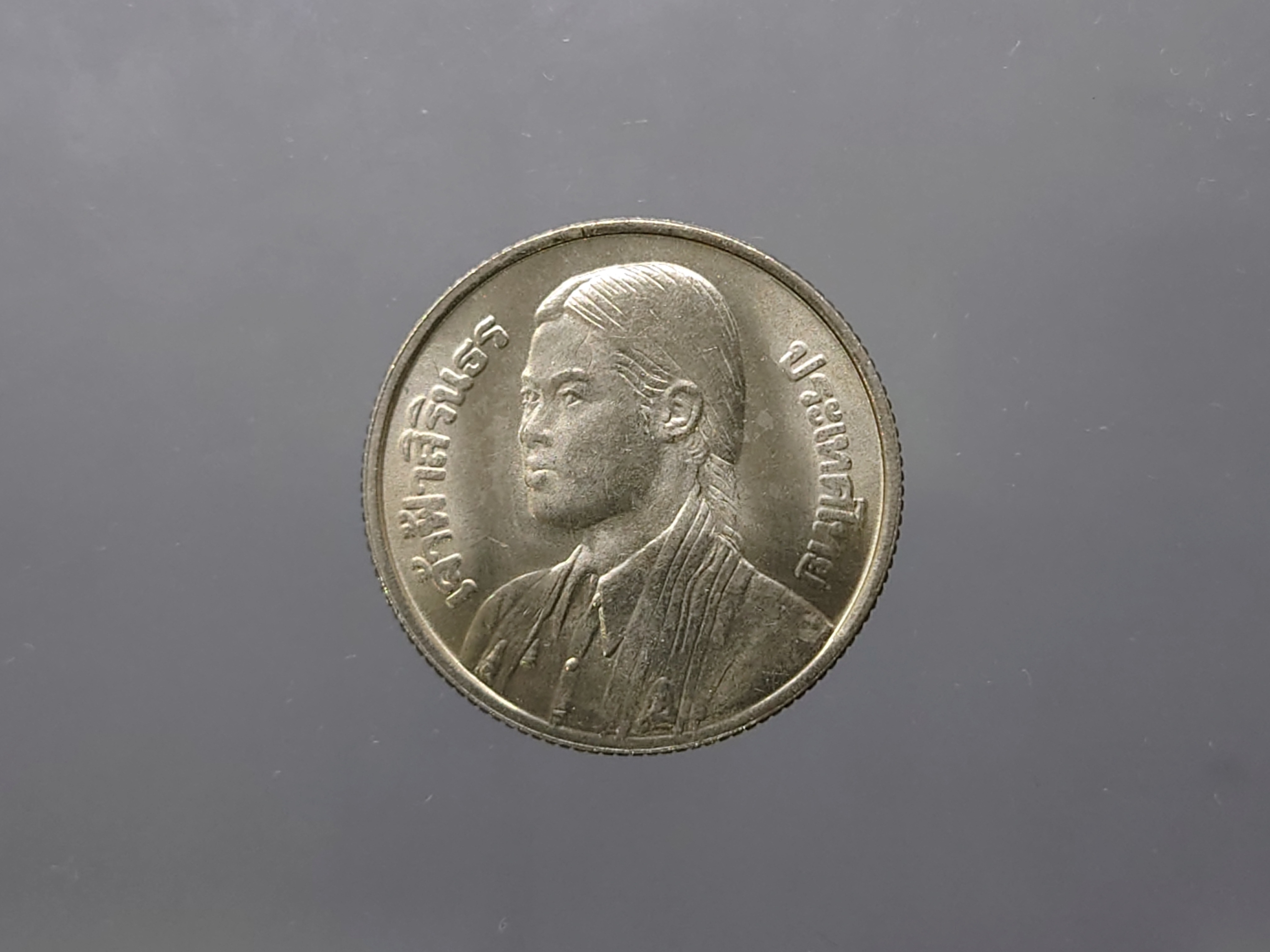 เหรียญ 1 บาท ที่ระลึกเจ้าฟ้าสิรินธรเทพรัตนสุดาฯ ทรงสำเร็จปริญญา บัณฑิตองค์แรก มหาลัยแห่งประเทศไทย ปี2520 ไม่ผ่านใช้