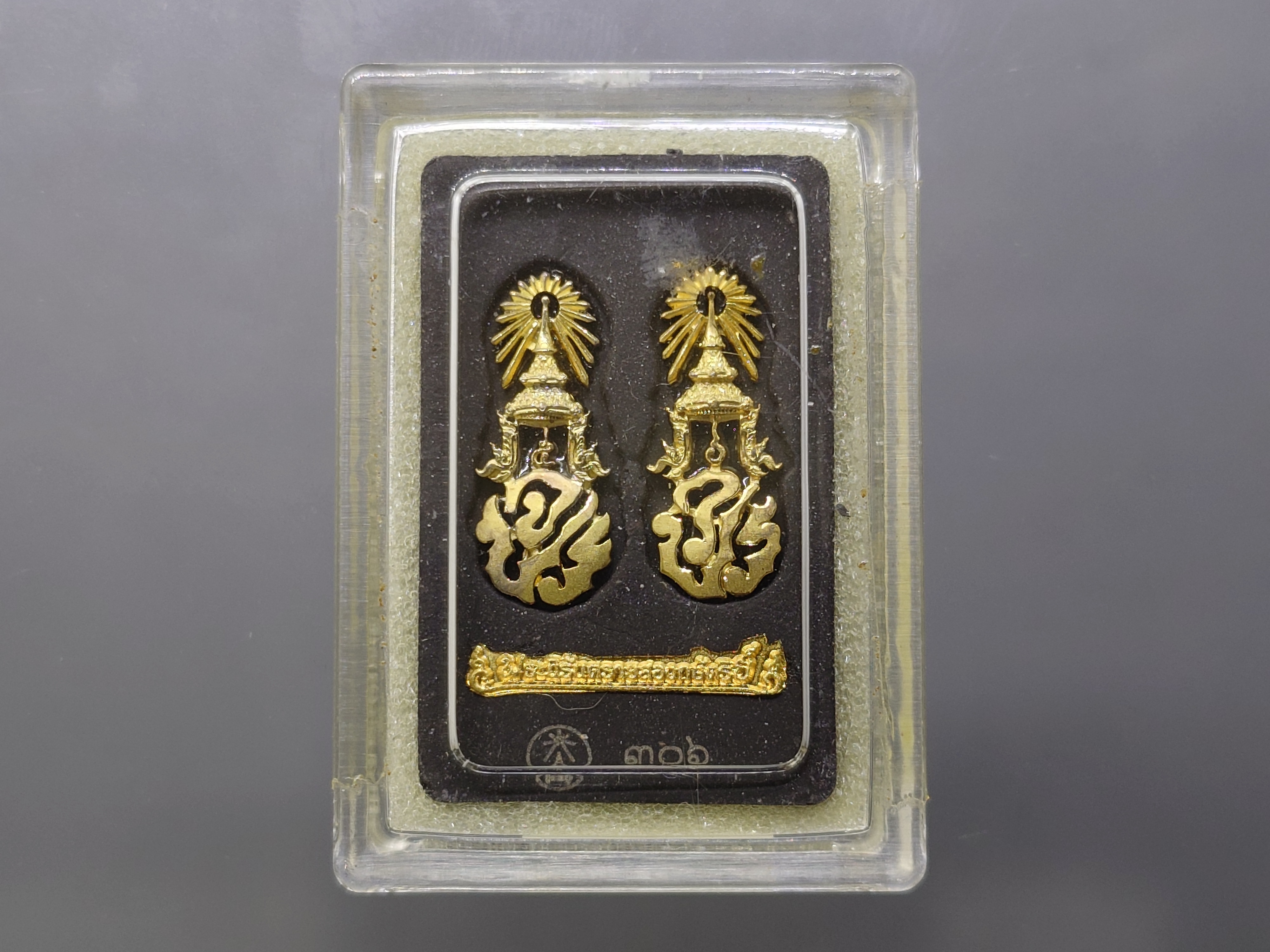 พระนิรันตรายสองกษัตริย์ มหาพุทธานุภาพแห่งแผ่นดิน เนื้อผง (สีดำ) หน้าปัดทอง หลังฝังโลหะเงินชุบทอง (พระปรมาภิไธยย่อสองกษัตริย์) ขนาดสูง 3.2 เซน ปี2552 พร้อมกล่องเดิม