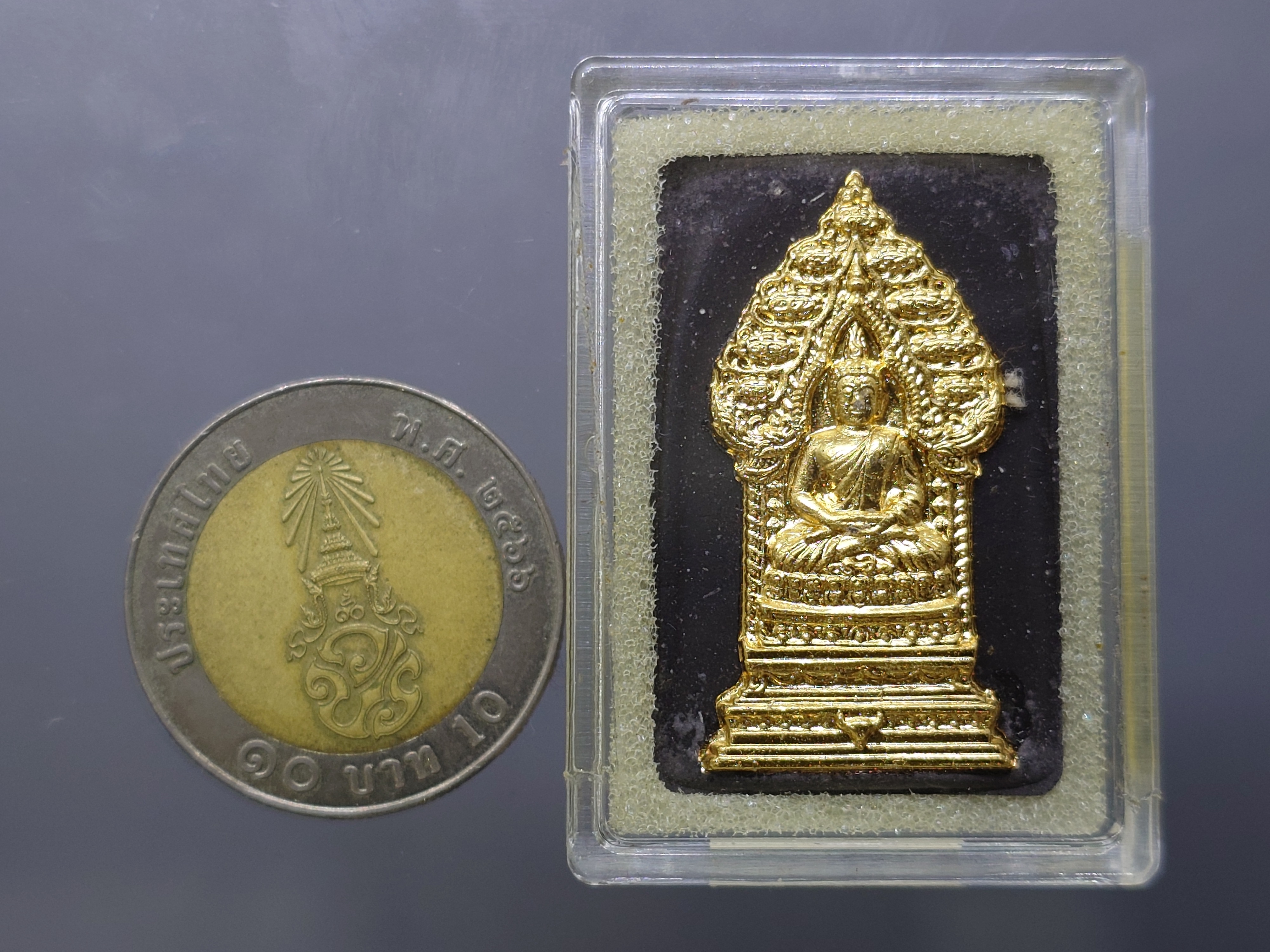 พระนิรันตรายสองกษัตริย์ มหาพุทธานุภาพแห่งแผ่นดิน เนื้อผง (สีดำ) หน้าปัดทอง หลังฝังโลหะเงินชุบทอง (พระปรมาภิไธยย่อสองกษัตริย์) ขนาดสูง 3.2 เซน ปี2552 พร้อมกล่องเดิม